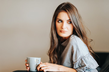 Young beautiful woman resting on the couch, holding cup of tea