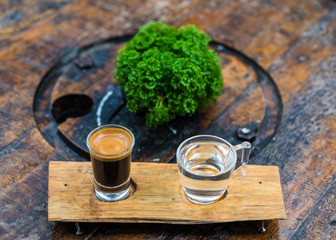 Espresso coffee cup serve with glass of water on wooden table