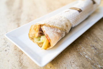 Tasty turkish kebab in tortilla wrap serving on white plate