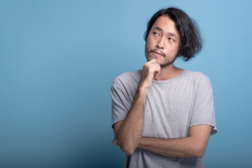 Young bearded man thinking pose in blue background.