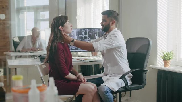 Male doctor examines thyroid gland of young girl