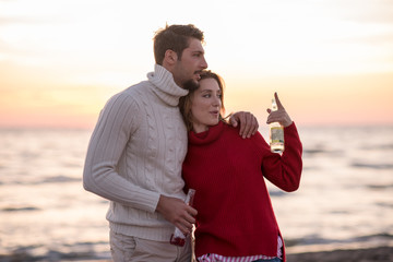 Naklejka premium Couple hugging and drinking beer together at the beach