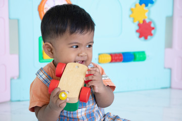 cute little asian baby boy bite wooden toy