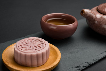 side view studio shoot of modern style Chinese mooncake with tea and teapot on black background