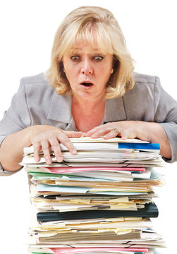 Mature woman trying to stop the pile of work from toppling