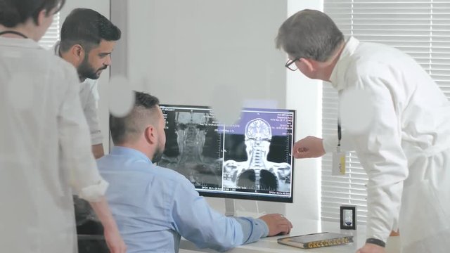 Team of doctors of research Institute studying x-ray image of human brain on computer. Scientists are studying diseases of human brain