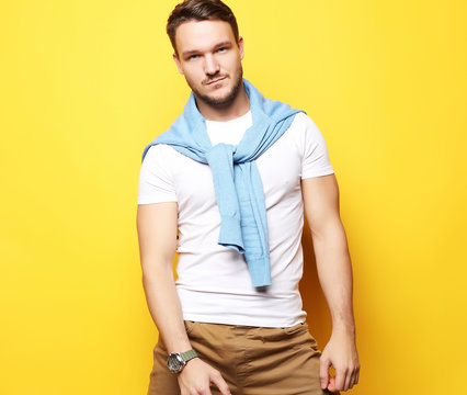 Portrait of a handsome young man, fashion model. Posing over yellow wall. Lifestyle and fashion concept.