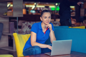 Young beautiful woman studying or working with laptop computer in neighborhood cafe