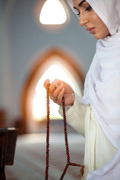 Young muslim woman praying in mosque with quran