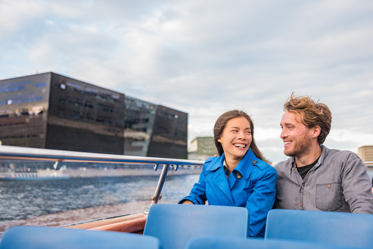 Copenhagen tourists couple on city boat cruise tour enjoying view of the black diamond Royal library, famous architecture building, Denmark, Europe travel. People traveling.