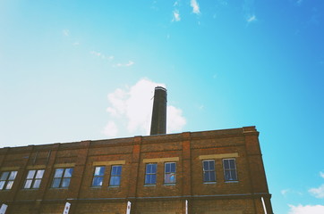 Old red brick factory building against blue sky