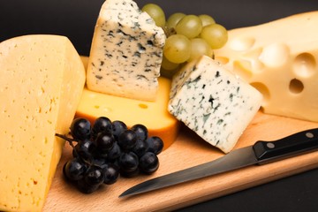 Knife, Cheese and Grape on the Wooden Platter on Black