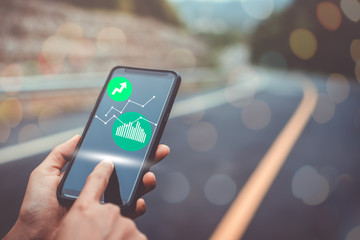 Woman hand using smartphone or tablet to do business, financial or trading stock forex market in park outdoor nature road background.