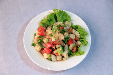Cellophane noodles salad with Vietnamese Pork Sausage and variety vegetable such as lettuce, tomato and onion in the round plate on the white floor.