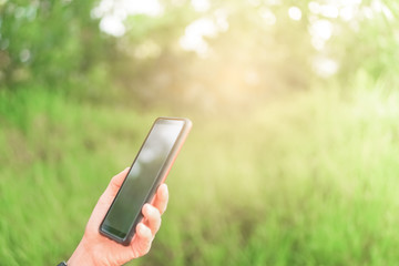 Copy space lady hand using smartphone with green nature abstract background.