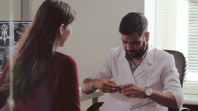 Young caucasian girl visit to indian male doctor in medical office