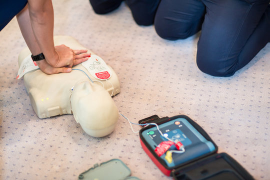 CPR training using and an AED and bag mask valve on an adult training manikin.  First aid cardiopulmonary resuscitation course using automated external defibrillator device, AED.