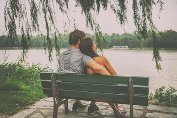 China travel. Young couple tourists sitting in love on a park bench looking at lake. Beijing summer palace, famous tourist attraction. Happy honeymoon vacation concept.