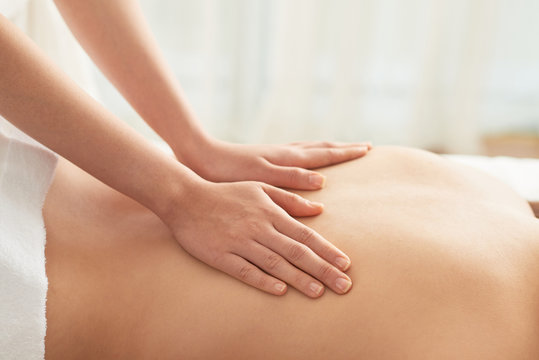Hands of woman massaging back of female client