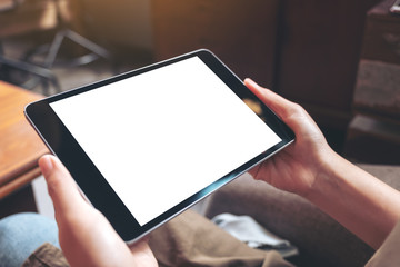 Mockup image of woman's hands holding black tablet pc with blank white desktop screen while sitting in cafe