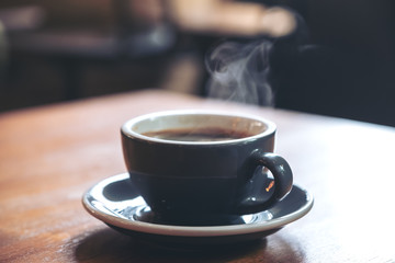 Closeup image of a blue cups of hot coffee with smoke on vintage wooden table in cafe