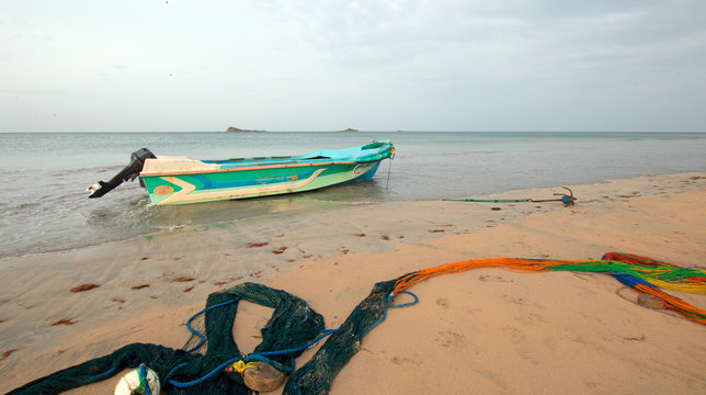 Small fishing boat next to curving fishing nets drying on Nilaveli beach in Trincomalee Sri Lanka Asia
