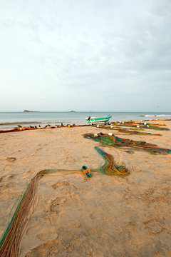 Small fishing boat beached next to fishing nets drying on Nilaveli beach in Trincomalee Sri Lanka Asia