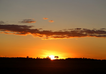 Beautiful photo of a bright sunset with clouds over a field