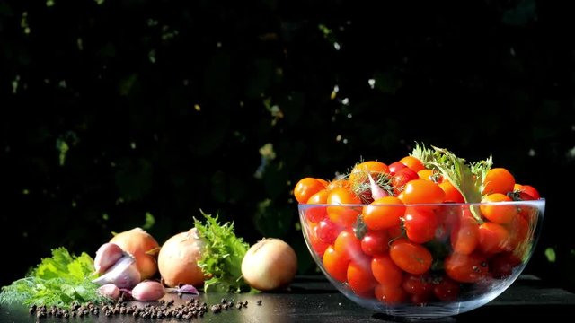 On a dark table spin plate with tomatoes, next to the onions, garlic, greens, pepper. Futa for the advertisement of sauces based on tomatoes.