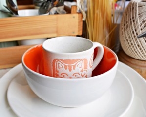 Funny cup with cat and white plates on the table