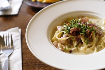 Italian cuisine, Spaghetti Cabana or Spaghetti White Sauce on white dish at restaurant on wooden background