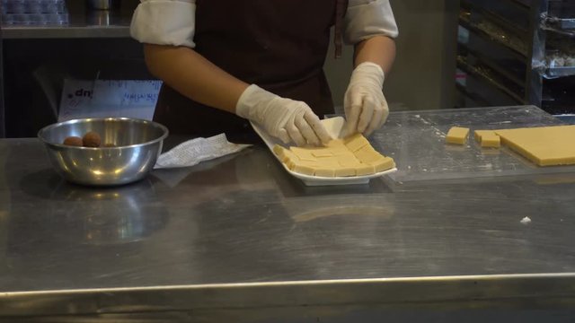 Woman made white chocolate powder falls sifting on chocolate bars and arrange down the dish
