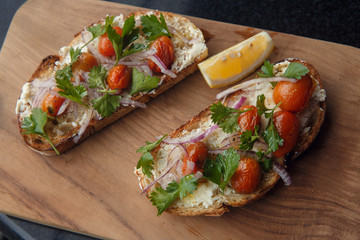 Open sandwich, toast, bruschetta with goat cheese, sun-dried tomatoes and arugula, served on the wooden Board. Healthy eating