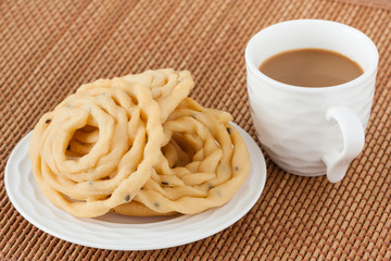 Indian murukku snack with coffee - A closeup of traditional deep fried Indian snack murukku on a plate served with coffee.