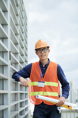 Young Asian construction engineer in glasses posing on construction site