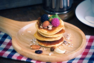 Pancake with berries with nut and cereal on wood plate.