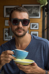 Young happy man drinks coffee in a restaurant or cafe