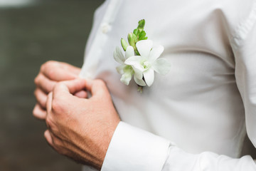 Groom boutonniere with white orchids on white shirt