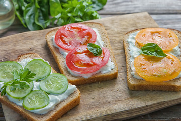 Crostini with toasted gray bread, cottage cheese and slased red and orange color tomatoes and slased cucumber