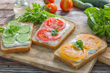Crostini with toasted gray bread, cottage cheese and slased red and orange color tomatoes and slased cucumber
