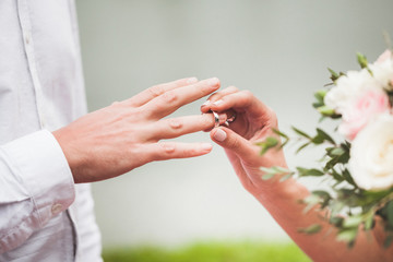 Obraz na płótnie Canvas Groom wearing ring on bride's hand on wedding ceremony close-up