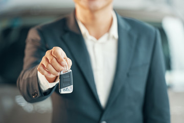 Cropped image of car dealership salesman giving keys