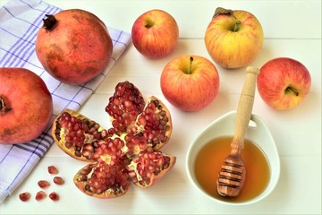 Opened ripe pomegranate and apples with honey in a bowl, Rosh Hashanah celebration. 