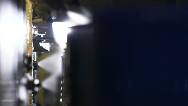 camera shows metal tanks cleaned with water on conveyor
