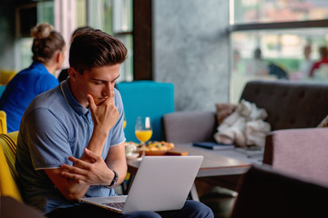 Young skilled male freelancer starting working day early in morning drinking coffee to wake up