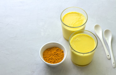 Golden milk with turmeric in a glass on a gray stone background. healthy natural energy drink. selective focus. free space
