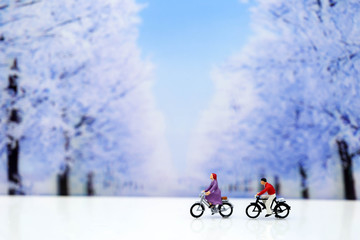 Miniature people : Travelers riding bicycle with winter background,traveling or exploring the world, budget travel