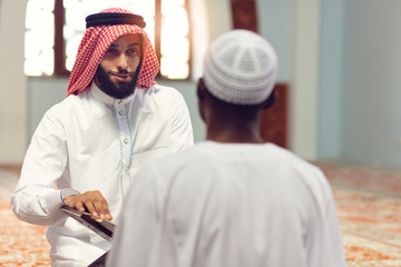 Two religious muslim man praying together inside the mosque