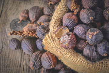 Black cardamom pods with open shell in gunny bag and Indian spice on wooden table background.