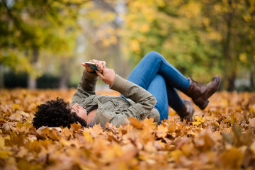 Teen girl using her mobile while lying in the park
